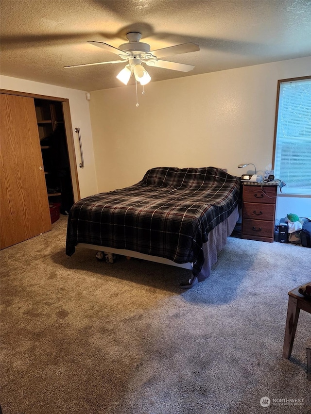 bedroom with a textured ceiling, carpet flooring, and ceiling fan