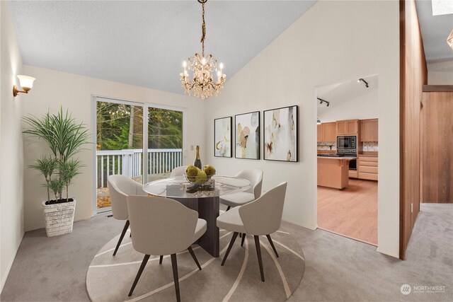 dining space featuring light carpet, high vaulted ceiling, and an inviting chandelier