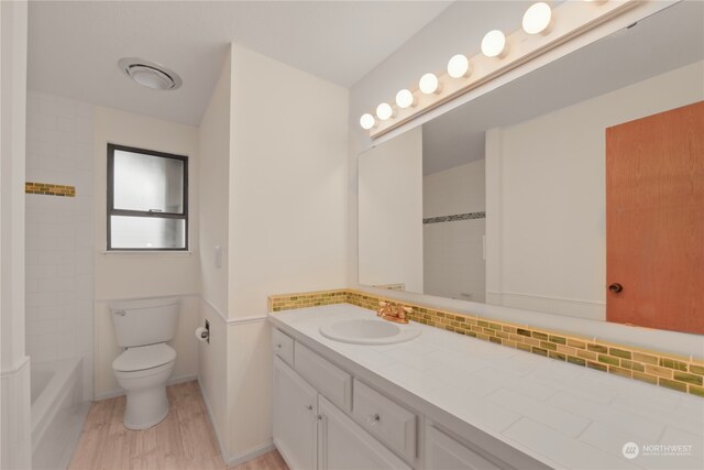 bathroom featuring decorative backsplash, hardwood / wood-style floors, vanity, and toilet