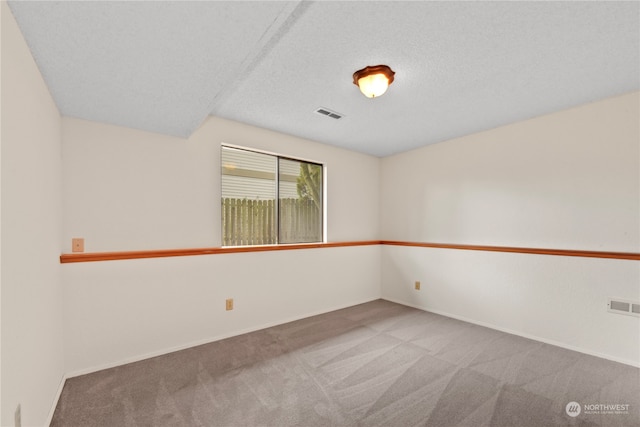 carpeted spare room with a textured ceiling