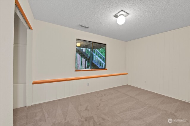 spare room with light colored carpet and a textured ceiling