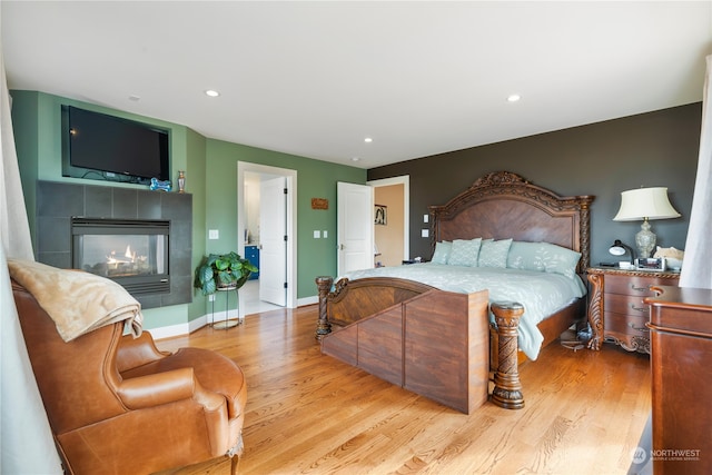 bedroom with light wood-type flooring, a fireplace, baseboards, and recessed lighting