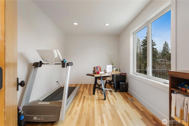 exercise room featuring radiator, recessed lighting, wood finished floors, and baseboards