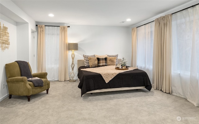 bedroom with light colored carpet and multiple windows