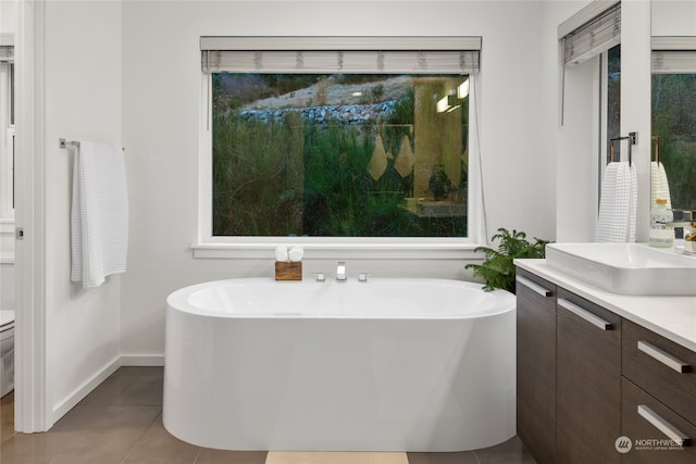 bathroom with tile patterned flooring, vanity, toilet, and a bath