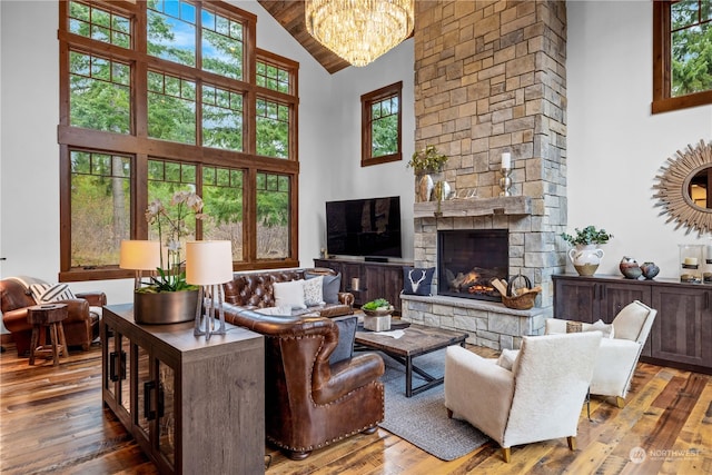 living room with a stone fireplace, plenty of natural light, high vaulted ceiling, and wood-type flooring