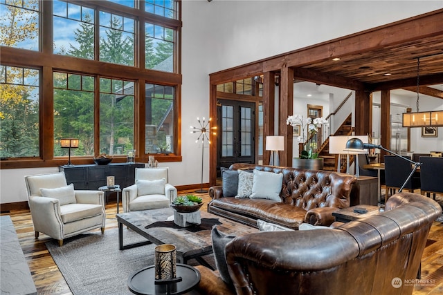 living room featuring a towering ceiling, beamed ceiling, and hardwood / wood-style flooring