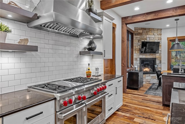 kitchen featuring white cabinetry, wall chimney exhaust hood, double oven range, decorative backsplash, and light wood-type flooring