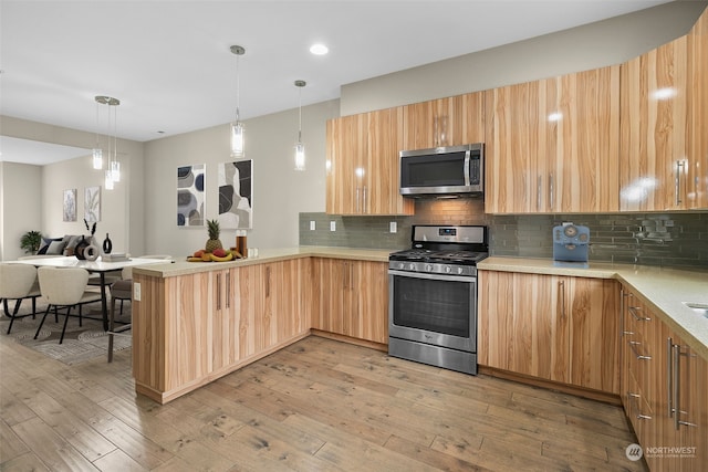 kitchen featuring backsplash, kitchen peninsula, light wood-type flooring, and appliances with stainless steel finishes