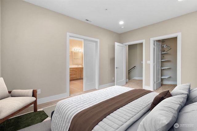 carpeted bedroom with ensuite bathroom and a spacious closet