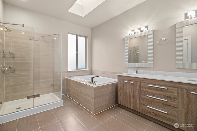 bathroom featuring tile patterned flooring, vanity, a skylight, and separate shower and tub