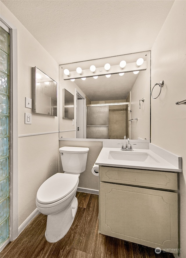 bathroom with vanity, a shower with door, hardwood / wood-style flooring, toilet, and a textured ceiling