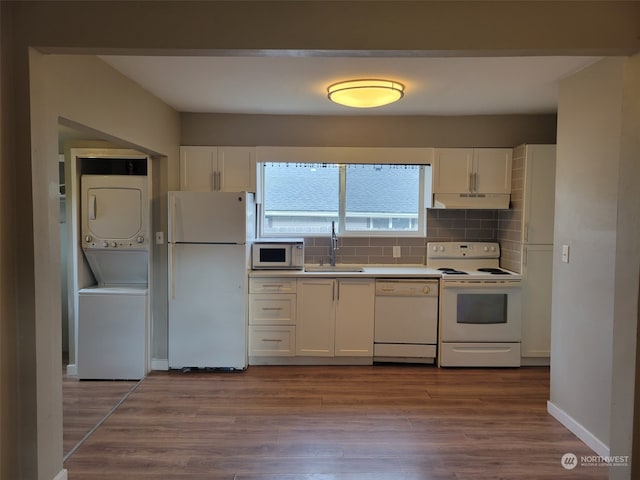 kitchen featuring stacked washer and clothes dryer, white cabinets, and white appliances