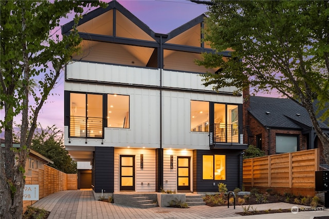 back house at dusk featuring a balcony