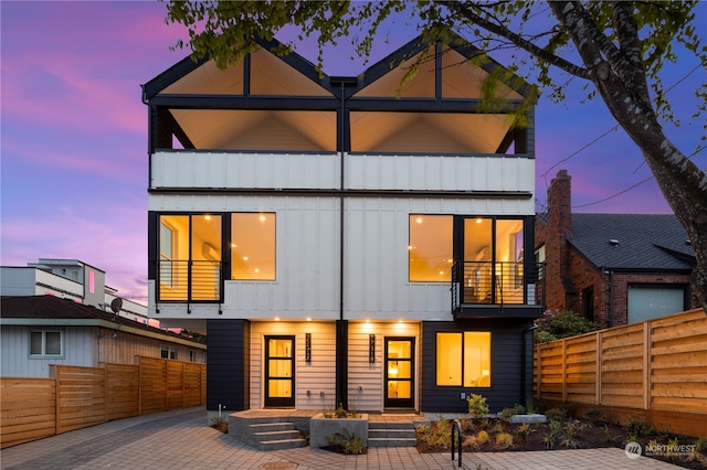 back house at dusk featuring a balcony