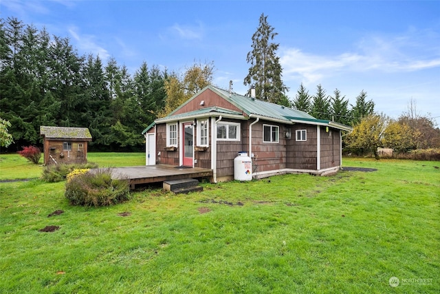 rear view of property featuring a storage shed and a yard