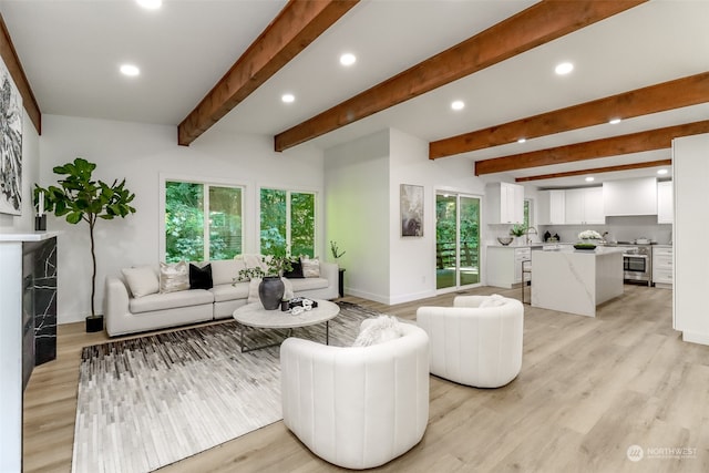 living room featuring beamed ceiling and light hardwood / wood-style floors