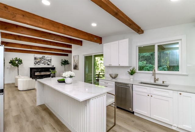 kitchen featuring dishwasher, beam ceiling, a kitchen bar, and white cabinetry