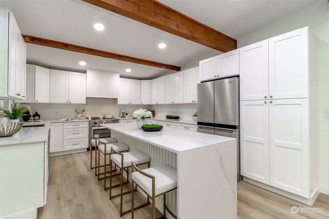 kitchen with beam ceiling, white cabinetry, a kitchen island, and custom range hood