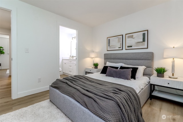 bedroom with ensuite bathroom and light hardwood / wood-style flooring