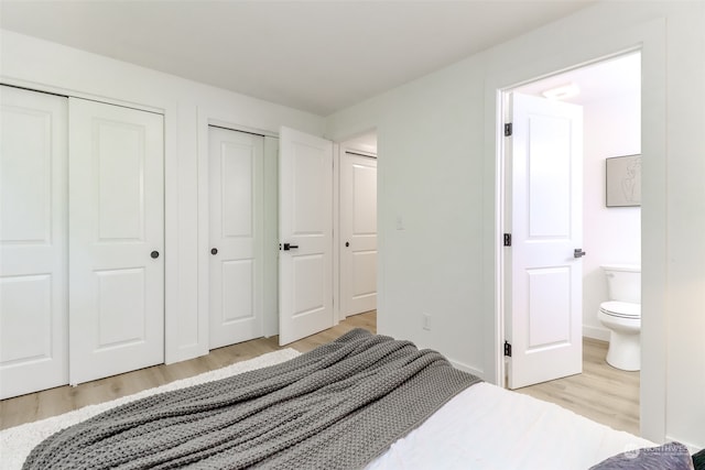 bedroom featuring connected bathroom, multiple closets, and light hardwood / wood-style floors