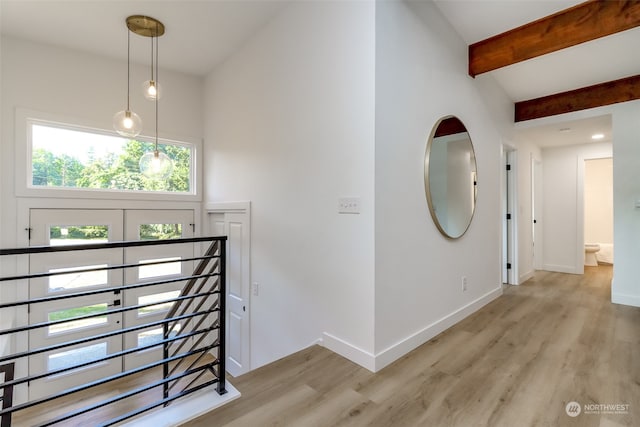 hall with beam ceiling and light wood-type flooring