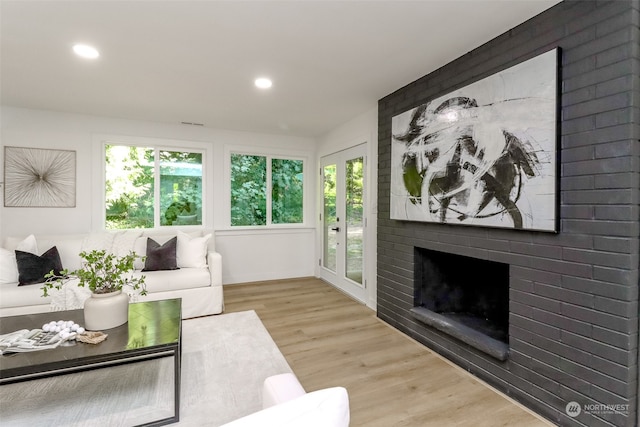 living room featuring a brick fireplace and light wood-type flooring