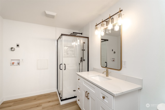 bathroom with hardwood / wood-style floors, vanity, and a shower with door