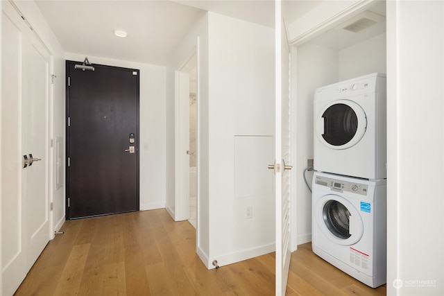 washroom featuring stacked washer and dryer and light hardwood / wood-style flooring