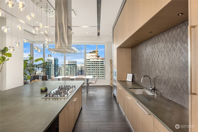 kitchen featuring sink, tasteful backsplash, dark hardwood / wood-style flooring, island exhaust hood, and stainless steel gas stovetop