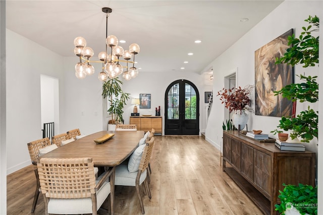 dining room with a chandelier, french doors, and light hardwood / wood-style flooring