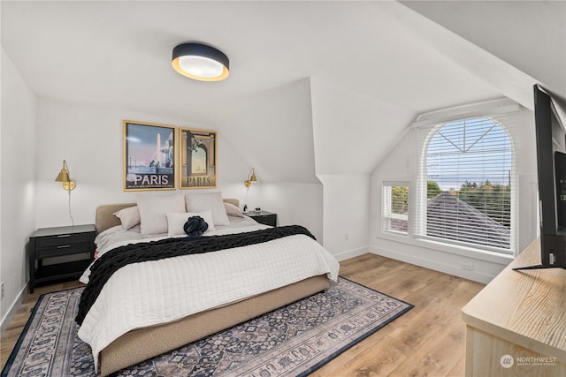 bedroom with hardwood / wood-style floors and lofted ceiling