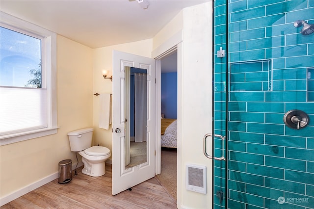 bathroom featuring toilet, plenty of natural light, a shower with shower door, and hardwood / wood-style flooring