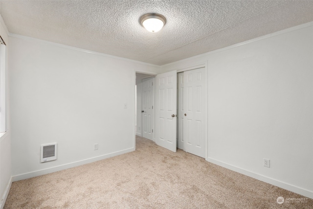 unfurnished bedroom with a textured ceiling, light colored carpet, heating unit, and a closet