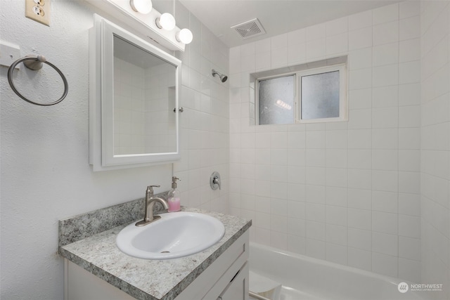 bathroom featuring vanity and tiled shower / bath