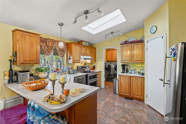 kitchen with stainless steel appliances, separate washer and dryer, kitchen peninsula, decorative light fixtures, and a breakfast bar area