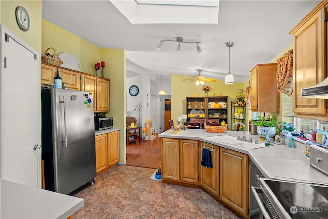 kitchen featuring a skylight, ceiling fan, sink, stainless steel appliances, and pendant lighting