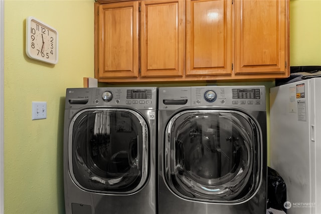 laundry room featuring washer and dryer and cabinets