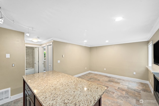 kitchen with a kitchen island, ornamental molding, and light stone counters