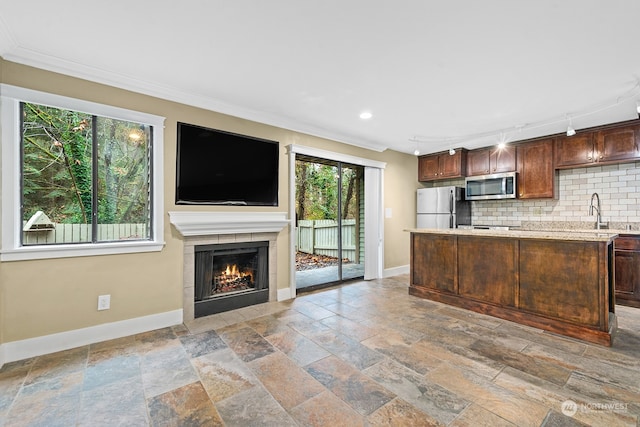 kitchen featuring rail lighting, tasteful backsplash, ornamental molding, dark brown cabinetry, and stainless steel appliances