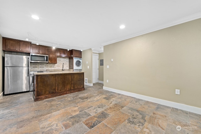 kitchen with appliances with stainless steel finishes, backsplash, a kitchen island with sink, crown molding, and washer / clothes dryer