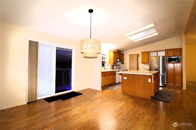 kitchen with a kitchen island, appliances with stainless steel finishes, hanging light fixtures, light hardwood / wood-style floors, and lofted ceiling with skylight