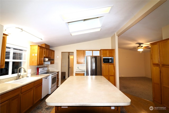 kitchen with appliances with stainless steel finishes, sink, lofted ceiling with skylight, ceiling fan, and a center island