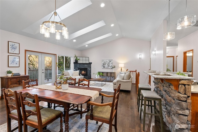 dining room with high vaulted ceiling, french doors, a stone fireplace, a skylight, and dark hardwood / wood-style floors