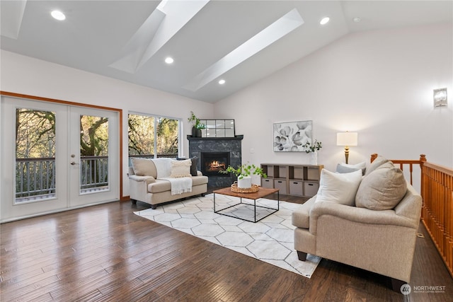 living room with high vaulted ceiling, french doors, a skylight, light hardwood / wood-style flooring, and a fireplace