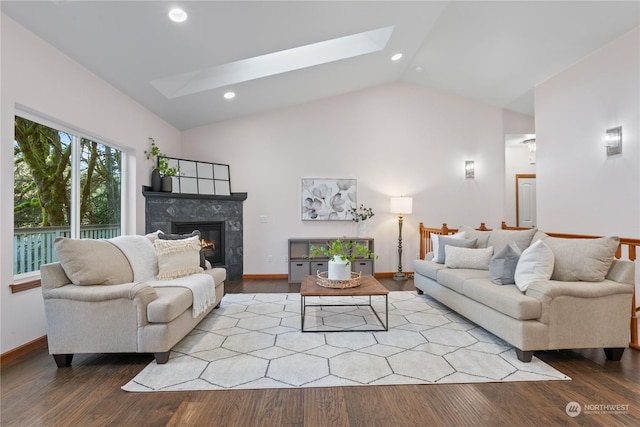 living room featuring a fireplace, light hardwood / wood-style flooring, and vaulted ceiling with skylight