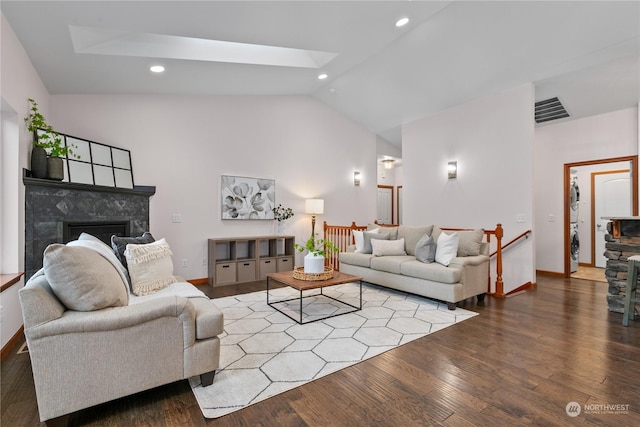 living room with hardwood / wood-style flooring, high vaulted ceiling, a skylight, and a premium fireplace