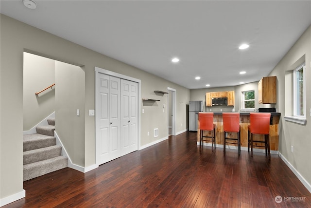 kitchen with a kitchen bar, kitchen peninsula, stainless steel appliances, and dark wood-type flooring