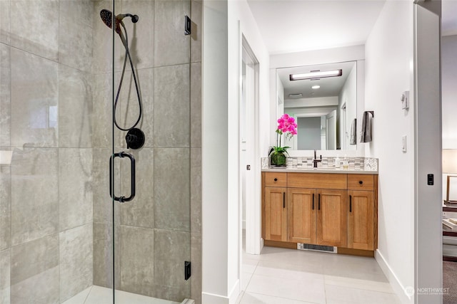 bathroom with tile patterned floors, vanity, a shower with door, and backsplash