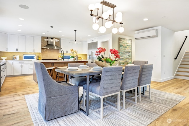 dining space featuring a chandelier, sink, light hardwood / wood-style floors, and a wall mounted air conditioner